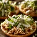 Close-up of delicious chicken sopes with toppings on a clean plate.