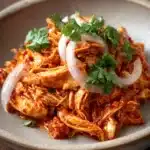 Close-up of Chicken Tinga with vibrant colors and textures, garnished with herbs.