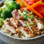 Close-up of a high protein chicken rice bowl with vibrant vegetables and a clean background.