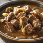 Close-up of keto beef tips and gravy in a crock pot with rich, hearty sauce.