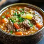Close-up of slow cooker beef barley soup with vegetables in a bowl