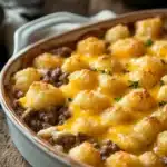 Close-up of tater tot casserole with ground beef, topped with melted cheese, perfect as a freezer meal.
