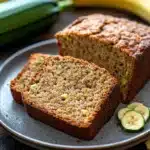 Close-up of zucchini bread with banana on a wooden board, showcasing texture and color.