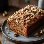 Close-up of banana bread coffee cake with a crumbly topping on a white plate.