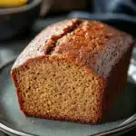 Close-up of homemade banana bread on a wooden board with a rustic background.