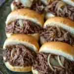 Close-up of a crock pot beef sandwich on a bun with a clean background.