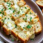 Close-up of a golden garlic bread casserole with crispy edges and melted cheese.