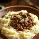 Close-up of a ground beef dinner with mashed potatoes on a white plate.
