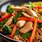 Close-up of high protein chicken lo mein with vegetables in a bright setting