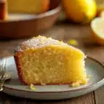 Close-up of a lemon cake with bright yellow frosting and lemon slices on top.