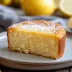 Close-up of a lemon cake without frosting on a white plate, showcasing its texture and color.