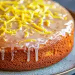 Close-up of a lemon cake with a slice cut out, showcasing its moist texture and bright yellow color.