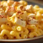 Close-up of creamy low calorie chicken mac and cheese in a white bowl with a sprinkle of herbs