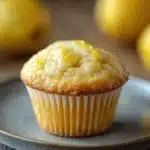 Close-up of a lemon yogurt muffin with a golden crust on a clean white background.