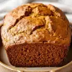 Close-up of pumpkin bread in a Dutch oven with a golden crust and warm lighting.