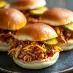 Close-up of slow cooker zesty BBQ chicken sliders with a clean background.