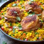 Close-up of a chicken yellow rice skillet with bright, warm lighting and clean background.
