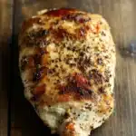 Crock pot chicken breast - the image shows a piece of grilled chicken on a wooden surface. the chicken appears to be seasoned with herbs and spices, giving it a golden brown color. the skin of the chicken is crispy and golden brown, indicating that it has been cooked to perfection. the wooden surface has a rustic and weathered appearance, with visible grain and knots. the background is blurred, making the chicken the focal point of the image.